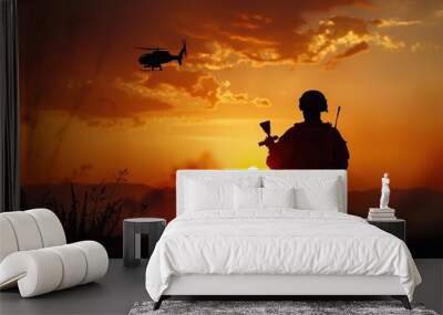 A man in a military uniform stands in a field at sunset, holding a rifle Wall mural