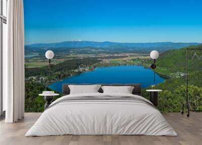 Breathtaking aerial view of a tranquil lake Klopein nestled amidst lush green forest in Carinthia, Austria. Crystal-clear water reflects vibrant blue sky. Rolling hills and mountains in Austrian Alps Wall mural