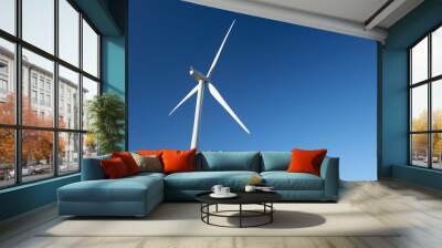 Close up of a single turbine from behind on a wind farm against a clear blue sky. Wall mural