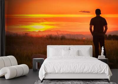 A young person enjoying a sunset over a mountain range Wall mural