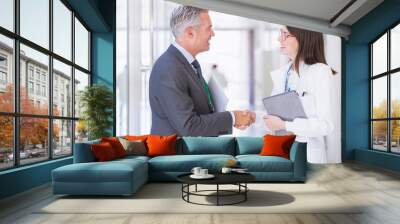 Scientist and businessman shaking hands in hallway Wall mural