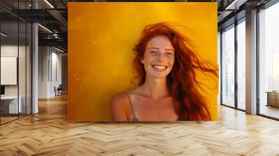 Happy smiling pretty redhead woman close up on a yellow background Wall mural