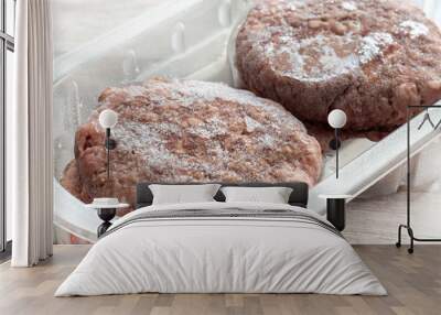 Frozen beef burgers in plastic tray packaging thawing.  On a grey wood background Wall mural