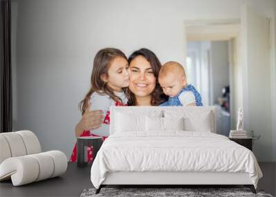 Happy woman hugging her adorable young daughters Wall mural