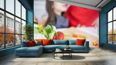 Little girl and her father slicing vegetables on a cutting board Wall mural