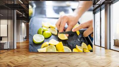 Male hands slicing lemons and limes on a black tray Wall mural