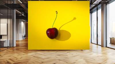 a single red cherry on a yellow background with a shade of cherry Wall mural