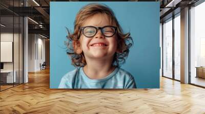 Portrait of a little boy in glasses on a blue background. Wall mural