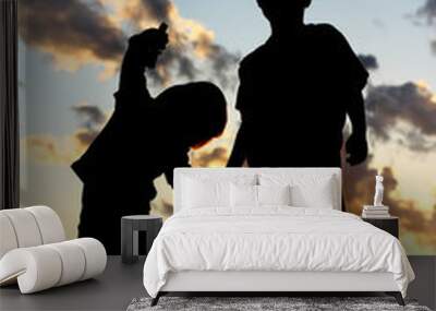 Silhouette of Young Children Holding Hands at Sunset Wall mural