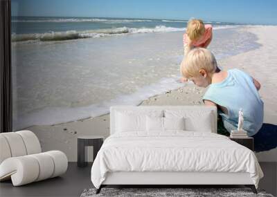 young children hunting for sea shells on the beach by the ocean Wall mural