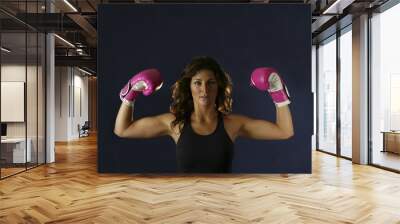 Young woman flexing with pink boxing gloves. Wall mural