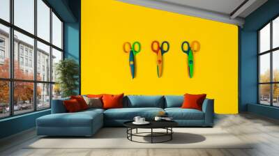 Safety colorful scissors isolated on the yellow background. Three colorful kids scissors. Zigzag, wave shape Wall mural