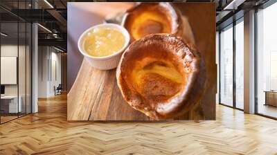 Two large savory Yorkshire puddings on a wooden serving dish with apple sauce in a dish served as an accompaniment to roast pork for a traditional English  sunday lunch Wall mural