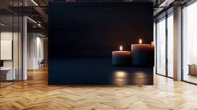 Three lit candles create a warm, tranquil glow against a dark background, evoking a peaceful and contemplative mood Wall mural