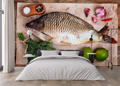 Fresh raw carp fish with lime, dill and garlic on old wooden background. Wall mural