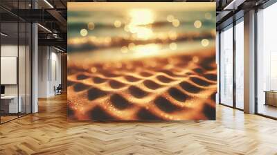 A close-up view of sandy beach dunes in the foreground, with a sparkling, sunlit ocean in the background. The ocean waves are softly blurred, creating a bokeh effect that highlights the glistening wat Wall mural