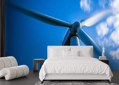 A close-up view of a wind turbine against a bright blue sky, showcasing renewable energy technology. Wall mural