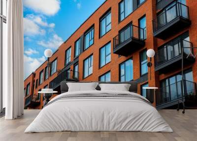 Modern brick apartment building featuring balconies and large windows under a blue sky. Wall mural