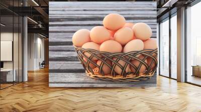 Chicken eggs in basket on wooden background Wall mural