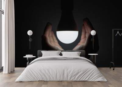 LED bulb with lighting in the human hand with dark background Wall mural