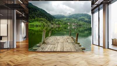 Reflections of green trees and a village into a calm lake as vie Wall mural