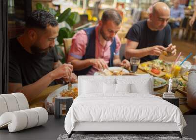 Group of Muslim people in restaurant enjoying Middle Eastern food. Selective focus Wall mural