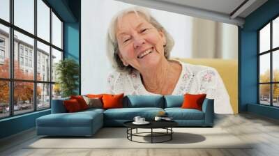 Face, smile and old woman on sofa with happiness at nursing home for elderly care and rehabilitation. Healthcare, laughing and portrait of happy person ion couch in house in retirement in living room Wall mural