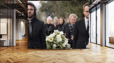 Pallbearers, men and walking with coffin at graveyard ceremony outdoor at burial place. Death, grief and group of people with casket at cemetery for funeral and family service while mourning at event Wall mural