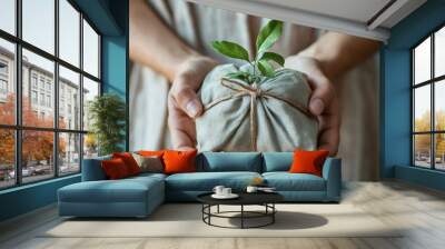 eco-friendly present wrapped in natural fabric, hands holding green plant for sustainable and thoughtful giving, perfect for eco-conscious occasions Wall mural