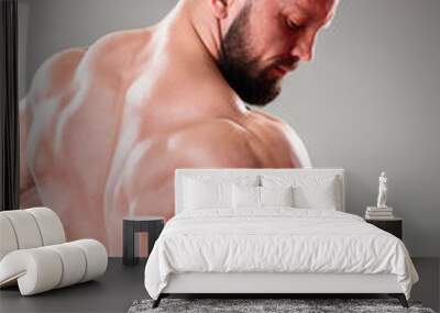 Close up of sexy muscular bodybuider posing on the gray background. Triceps contraction Wall mural