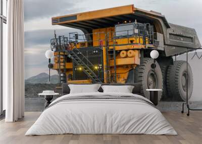 A dump truck drives through an open pit. Wall mural