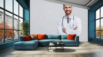 Smiling male physician in lab coat and stethoscope, displaying positive test results and looking at camera on white background with room for text. Wall mural