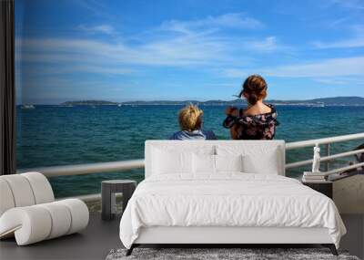 Children stand on the railing, with a view over the sea to Saint-Tropez Wall mural