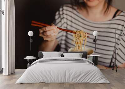 young woman eating instant noodles Wall mural