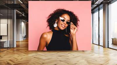 Beautiful african american girl with an afro hairstyle smiling. Portrait of happy young black woman laughing against pink wall.Blissful lovable woman with african hairstyle laughing indoor Wall mural