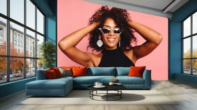 Beautiful african american girl with an afro hairstyle smiling. Portrait of happy young black woman laughing against pink wall.Blissful lovable woman with african hairstyle laughing indoor Wall mural