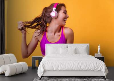 Cheerfully smiling mixed race sporty woman gains victory, isolated on orange  background Wall mural