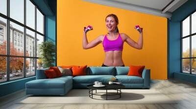 Close up portrait of delightful beautiful ideal slim sportive powerful muscular positive woman dressed in tight pink top demonstrating her biceps.Beautiful fitness woman showing her biceps Wall mural