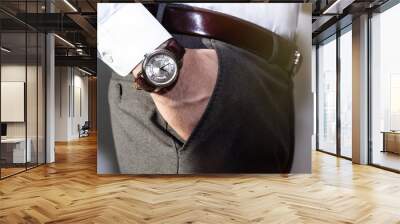 Closeup fashion image of luxury watch on wrist of man.body detail of a business man.Man's hand in a grey shirt with cufflinks in a pants pocket closeup. Tonal correction. Wall mural