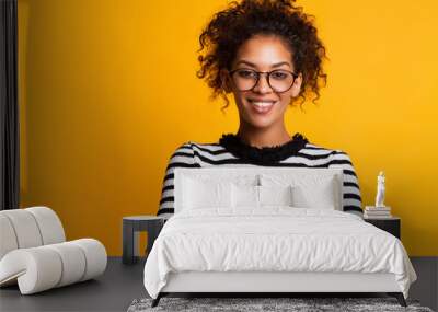 Indoor shot of beautiful happy African American student girl standing isolated in white studio smiling cheerfully Wall mural