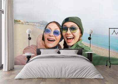 Mother and adult daughter are doing selfie on the beach going crazy and showing tongueSunset light.Happy and positive emotions.Hipster family.Parents and teenagers.Summer vacation self-portrait Wall mural