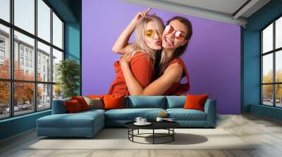 Two young women are having fun and friends are hugging each other.Two happy affectionate young woman hugging each other in a close embrace while laughing and smiling, young multiracial female friends. Wall mural