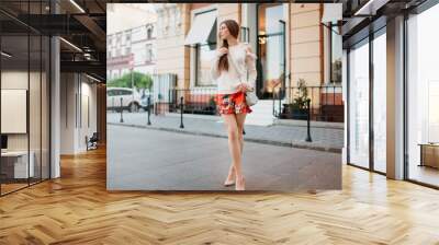 Young fashionable trendy girl posing in old city street.Close up summer sunny lifestyle fashion portrait of young stylish hipster woman walking on the street, wearing cute trendy outfit. Copy space. Wall mural