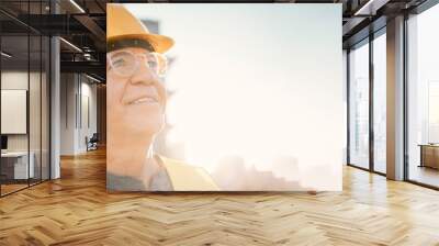 Senior man, builder and construction in the city with smile and helmet for safety or security at site on mockup. Elderly male contractor, engineer or technician face smiling with hard hat in town Wall mural