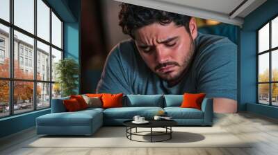 Sad depressed Hispanic man sitting in his living room, depression and loneliness, mental health concept. Vertical (2:3) Wall mural