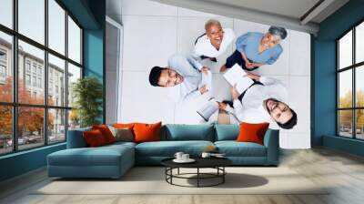 Collaboration, overhead and huddle with a business team laughing while working together in an office. Face, teamwork and documents with a man and woman employee group standing in a circle from above Wall mural