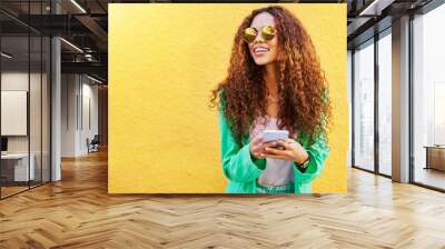 Fashion, phone and black woman isolated on wall background for social media, blog or creative ideas mockup. Funky model or thinking person on mobile app or smartphone with designer summer clothes Wall mural