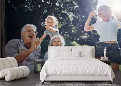 Grandparents, bubbles and children play in park happy together for fun, joy and outdoor happiness. Retired, smile and excited elderly senior couple, girl grandkids and love playing outside in nature Wall mural