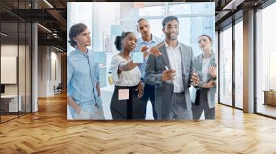 Teamwork, collaboration and planning with a team and their manager working on the vision, mission and strategy for their business. Writing on a glass wall with sticky notes for growth and development Wall mural