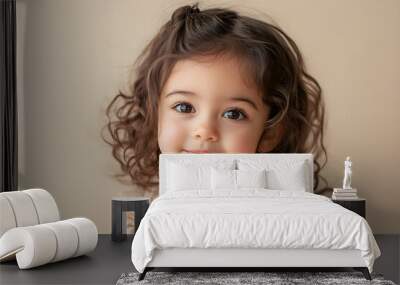 A young girl with curly hair is smiling at the camera Wall mural